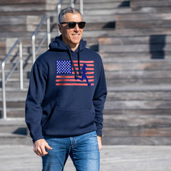 Man wearing a navy hoodie with an American flag design outdoors on steps.
