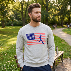 Man wearing a gray sweatshirt with an American flag and running figure design in a park.