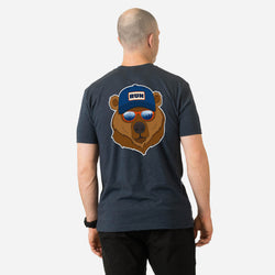 Person wearing a navy t-shirt with a bear graphic on the back, featuring a blue cap and sunglasses.
