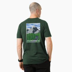 Man wearing a green t-shirt with a nature graphic on the back, standing against a white background