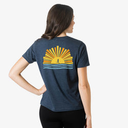 Person wearing a blue t-shirt with a sun graphic design on the back against a white background