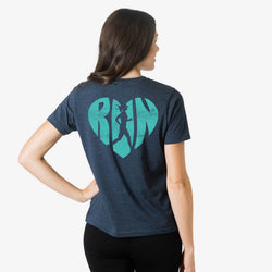 Woman wearing a navy t-shirt with a green heart-shaped runner logo on the back