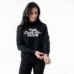 A woman wearing a black crewneck sweatshirt with 'THE Daily Run CLUB' printed in white across the chest, paired with black leggings, against a plain white background.