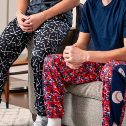 Two boys wearing sports lounge pants featuring patterned hockey and baseball designs