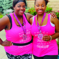 Two runners wearing pink tank tops with matching virtual race medals and "Miles of Friendship" race bibs