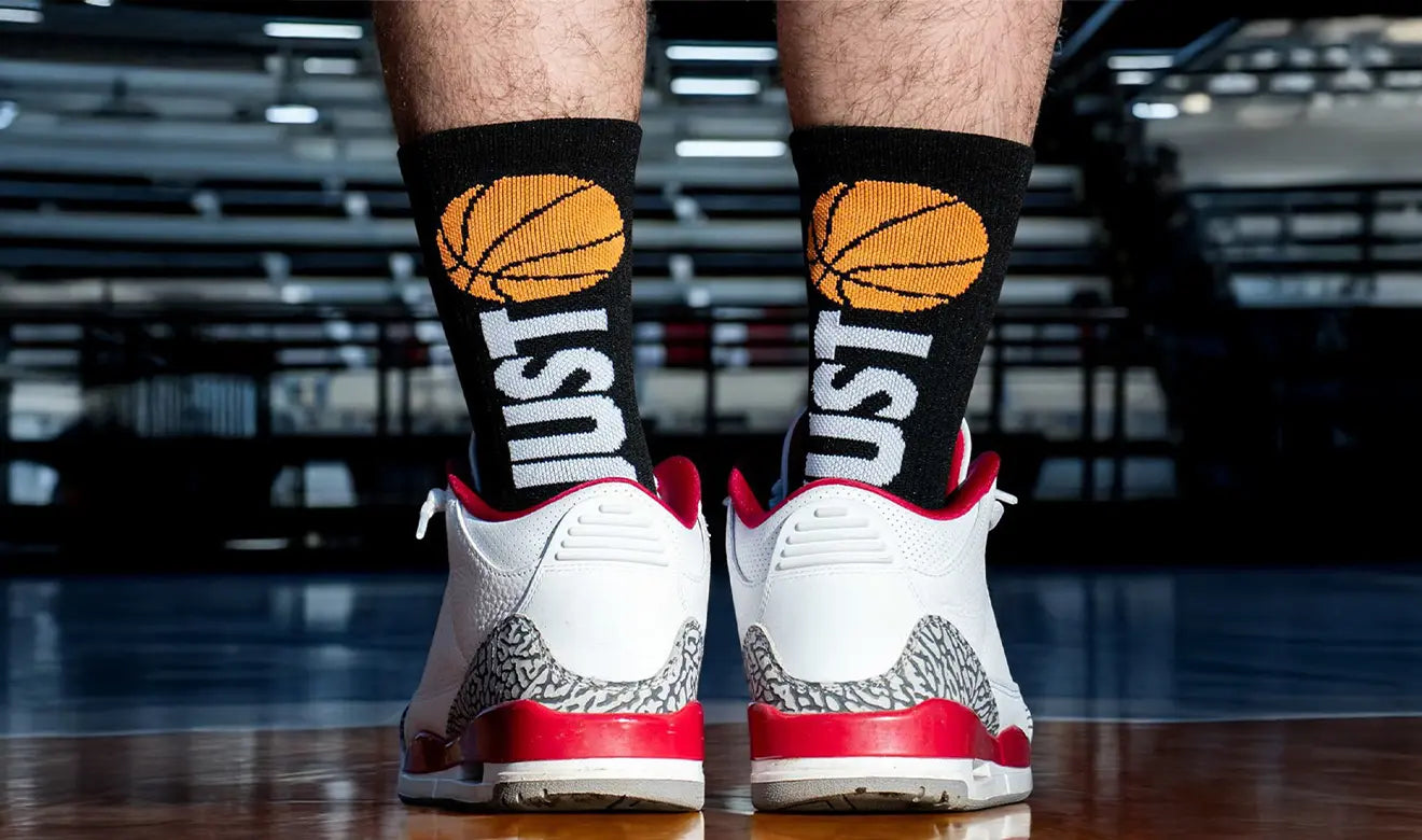 Person wearing red and white sneakers with basketball-themed socks in a gym setting