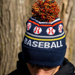 Boy wearing a navy blue baseball knit hat with pom-pom featuring woven baseball icons and the word Baseball.