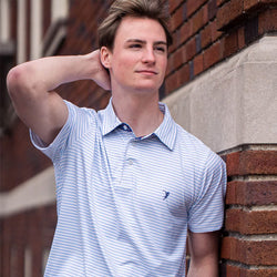 Teen wearing light blue and white striped lacrosse polo shirt with a small navy player silhouette logo.