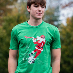 Teen wearing green lacrosse t-shirt featuring Santa Claus with a helmet and playing lacrosse graphic.