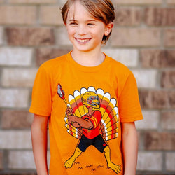 Youth wearing orange lacrosse t-shirt featuring a turkey wearing a helmet and holding a lacrosse stick.