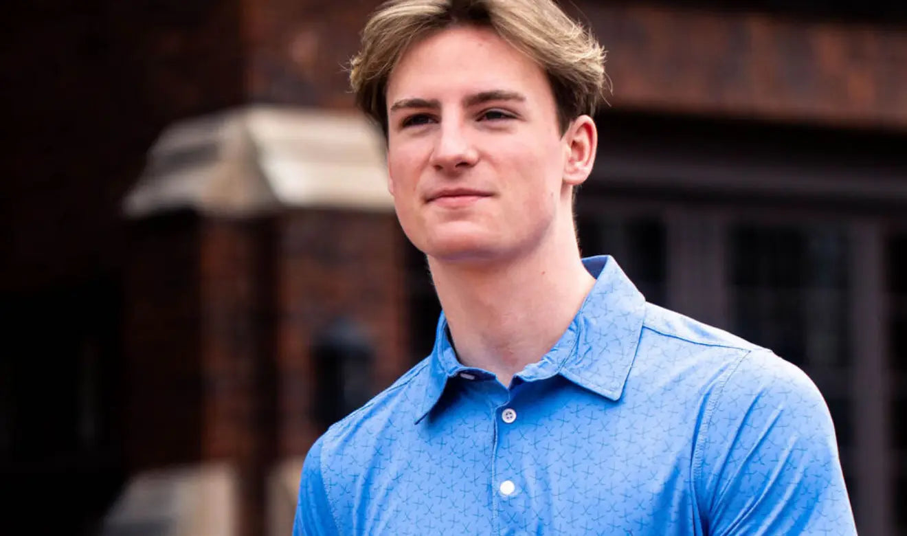 Man wearing a blue polo shirt standing outdoors with a blurred background