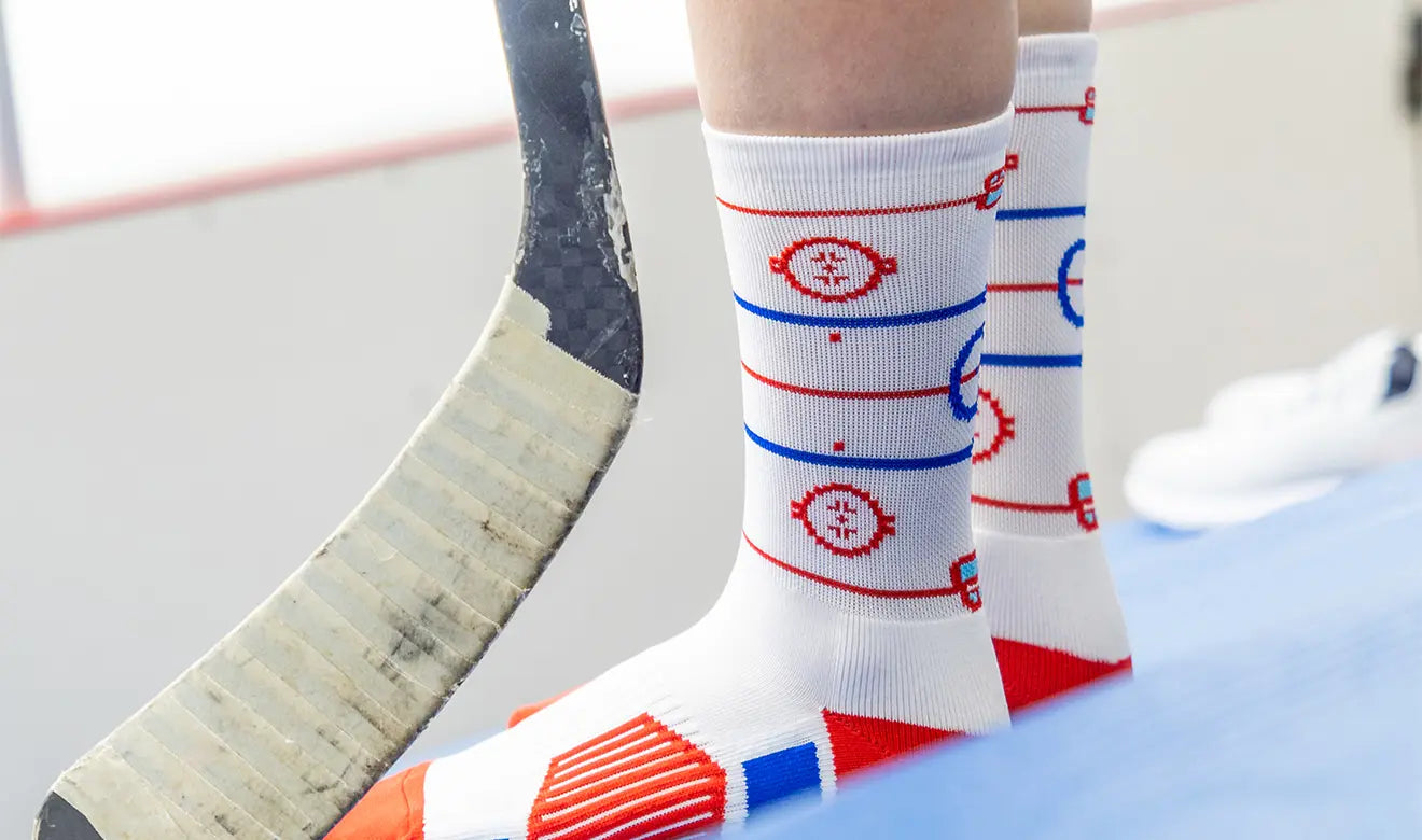 Person wearing socks with a sports theme design, holding a hockey stick