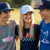 Three young people with sports themed hats and tees standing together on a grassy field, smiling.