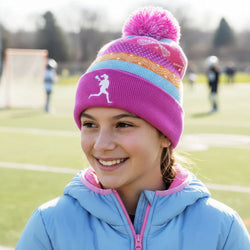 Girl wearing pink lacrosse knit hat with pom-pom featuring colorful stripes and a white player silhouette.