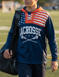 Youth wearing navy blue USA lacrosse lace-up hoodie featuring stars and stripes shoulder design and white crossed sticks graphic.