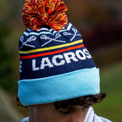 Navy blue lacrosse knit hat with pom-pom featuring crossed sticks pattern and woven Lacrosse text.