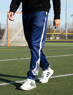 Navy blue lacrosse warm-up pants featuring white lacrosse stick side stripe and all-over pattern.