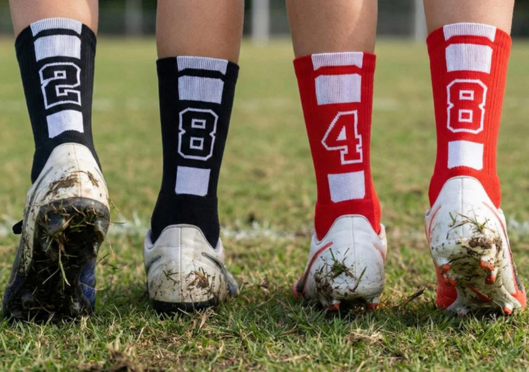 Person wearing soccer cleats and socks with numbers on a grassy field