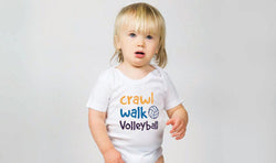 Child wearing a white baby onesie featuring "Crawl Walk Volleyball" text and a volleyball graphic.