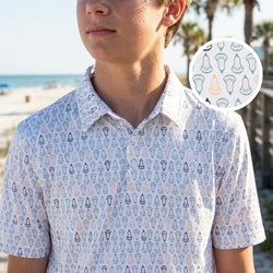 Person wearing a lacrosse patterned short sleeve performance polo shirt with a beach in the background