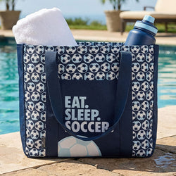 Navy tote bag with soccer ball pattern and 'Eat. Sleep. Soccer' text by a poolside.