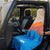 Person setting up a colorful towel on the back of an open Jeep in a natural setting.
