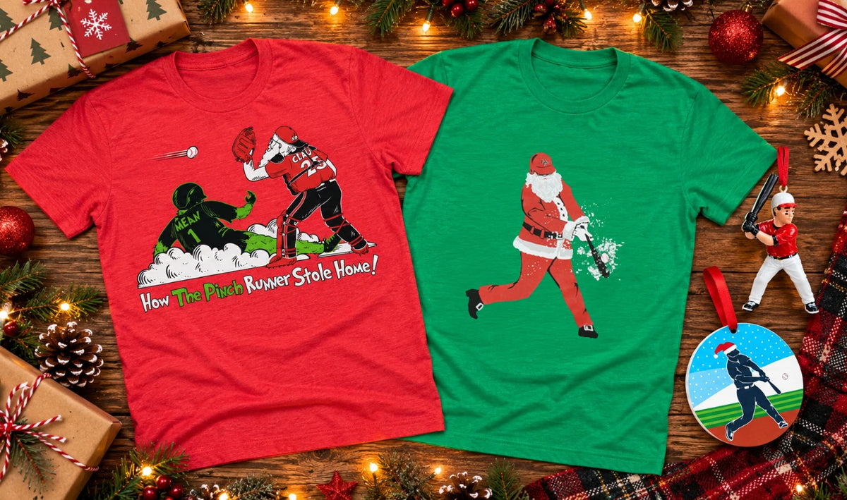 Two Christmas-themed graphic t-shirts displayed on a rustic wooden background decorated with pine branches, ornaments, and wrapped gifts