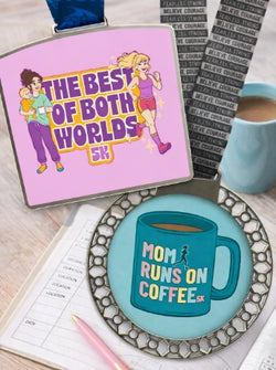 Pink sign with 'The Best of Both Worlds 5K' design, blue mug with 'Mom Runs on Coffee' design, and a notebook on a wooden surface.