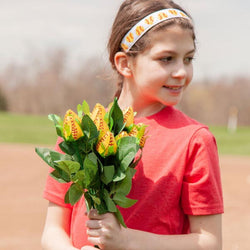Girl holding a softball rose bouquet and patterned headband