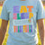 Girl wearing light blue volleyball t-shirt featuring colorful Eat Sleep Volleyball slogan and net graphic.