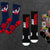 Six pairs of wrestling-themed crew socks arranged on a dark textured surface. The designs include navy and red socks with a wrestler graphic, black socks with 'JUST WRESTLE' text, black socks with a red, yellow, and white graphic, black socks with 'EAT SLEEP WRESTLE' text, and black socks with a white skull graphic.