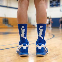 Person wearing blue socks with white basketball design and blue shoes on a basketball court.