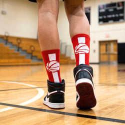 Person wearing red and white socks with a basketball design on a basketball court.