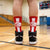 Person wearing red socks with basketball designs on a gymnasium floor.