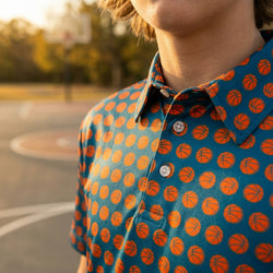 Person wearing a polo shirt with basketball pattern on an outdoor court