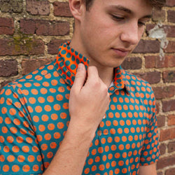 Youthwearing a blue and orange basketball polo shirt against a brick wall.