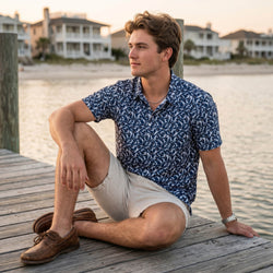 Teen wearing a blue basketball patterned polo shirt sitting on a pier.
