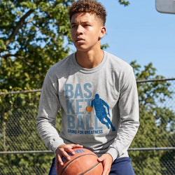 Person wearing a gray long-sleeve shirt with basketball design on an outdoor court