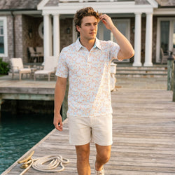 Teen wearing a basketball patterned polo shirt by a dock outdoors.