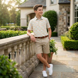 Young man in a basketball patterned polo shirt and beige shorts standing on a stone pathway.