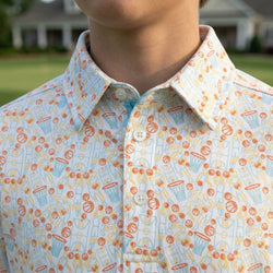 Close-up of a person wearing a basketball patterned polo shirt with a blurred outdoor background