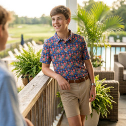 Young man in a colorful basketball polo shirt and beige shorts standing on a deck.