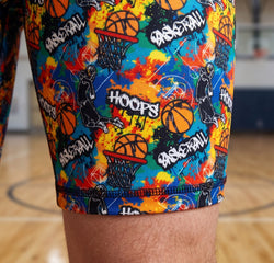 Colorful basketball-themed shorts on a person standing on a basketball court.