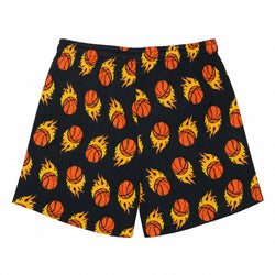 Black athletic shorts featuring a repeating pattern of orange basketballs surrounded by yellow and orange flames, displayed flat against a white background.
