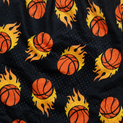 Close-up of a black mesh fabric printed with orange basketballs surrounded by yellow and orange flames.