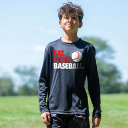 Child wearing a long-sleeve shirt with 'Eat. Sleep. Baseball.' text on a sports field.