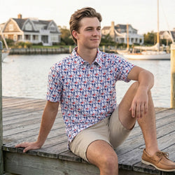 Teen wearing a patriotic baseball patterned polo shirt outdoors sitting by a pier.