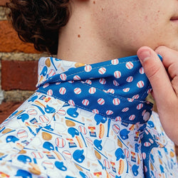 Close-up of a person wearing a colorful baseball patterned shirt with a brick wall background