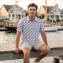 Teen wearing a baseball patterned polo shirt outdoors sitting on a dock.
