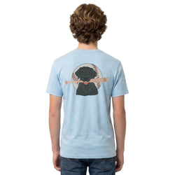 Person wearing a light blue t-shirt with a baseball dog graphic on the back, standing against a white background